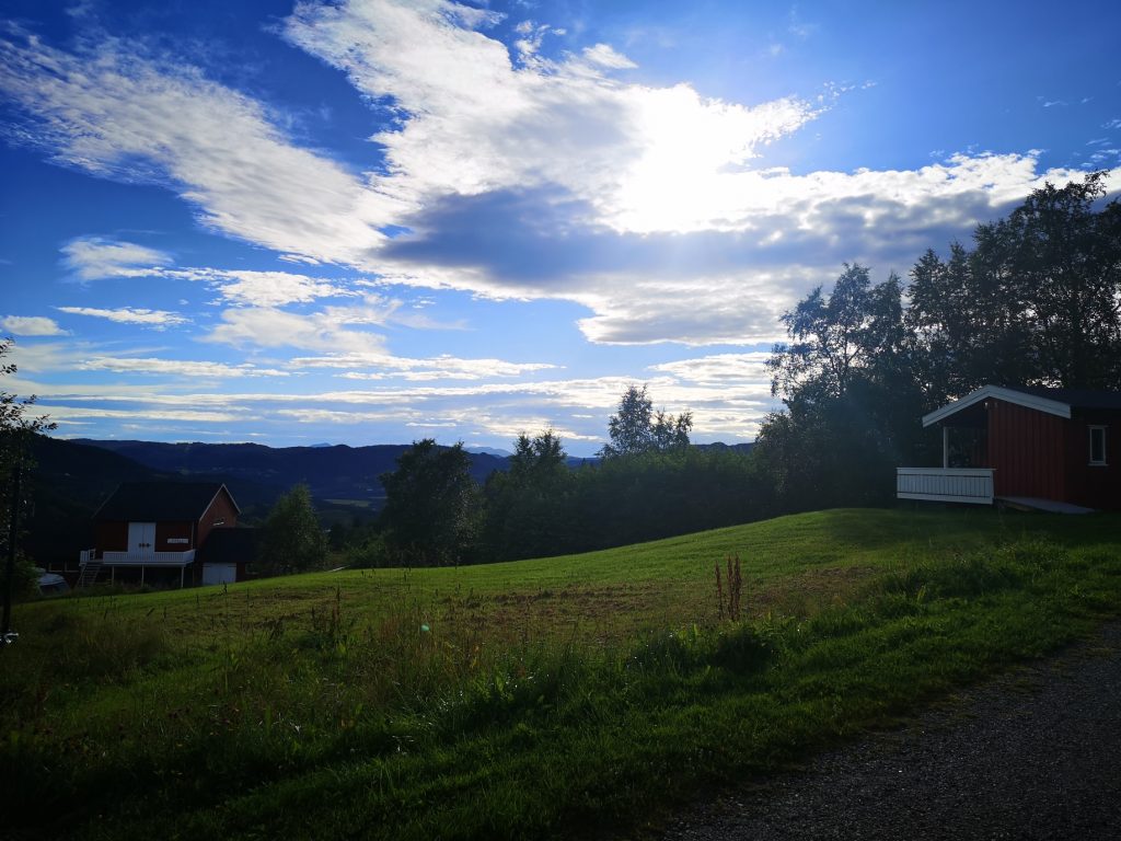 Cloudy, blue sky with a little bit of a view. Green grass.